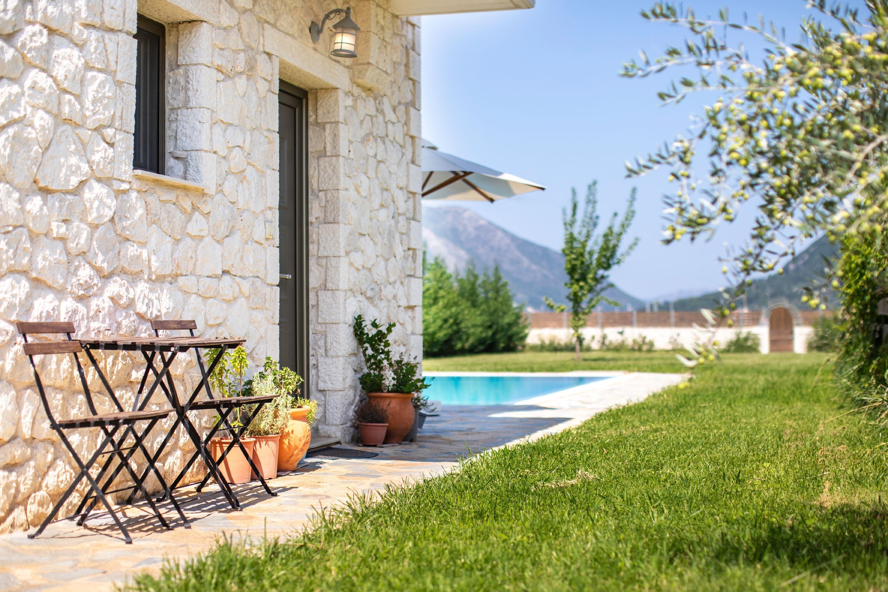 A stone building with a pool, outdoor seating, and potted plants.