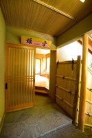 Quarto japonês tradicional com tatame, porta deslizante e cama com cabeceira baixa.