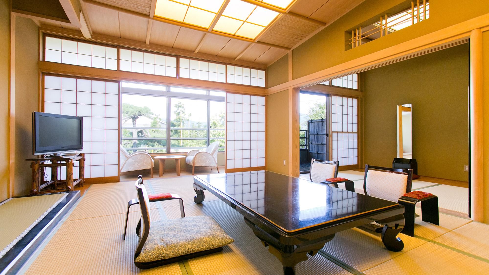 Ett traditionellt japanskt rum med tatamimattor på golvet, ett lågt bord, stolar och en tv.
