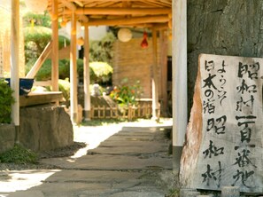Uma estrutura tradicional japonesa de madeira, com um caminho de pedra que a leva.