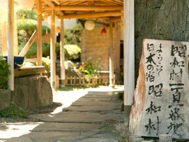 Uma estrutura tradicional japonesa de madeira, com um caminho de pedra que a leva.