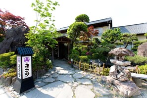 Ein traditioneller japanischer Garten mit einem Kiesweg, der zu einem Gebäude mit einem Ziegeldach führt.