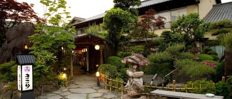 Um jardim japonês tradicional com um caminho de pedra, um banco de madeira e um farol de pedra.