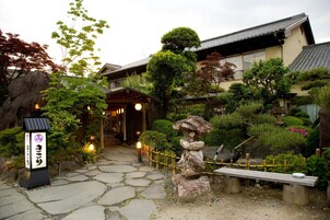 Um jardim japonês tradicional com um caminho de pedra, um banco de madeira e um farol de pedra.