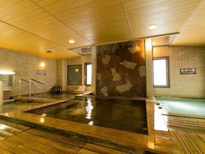 Ein großes Hallenbad mit Holzboden, Steinwand und einem Schild, das einen Erholungsbereich kennzeichnet.