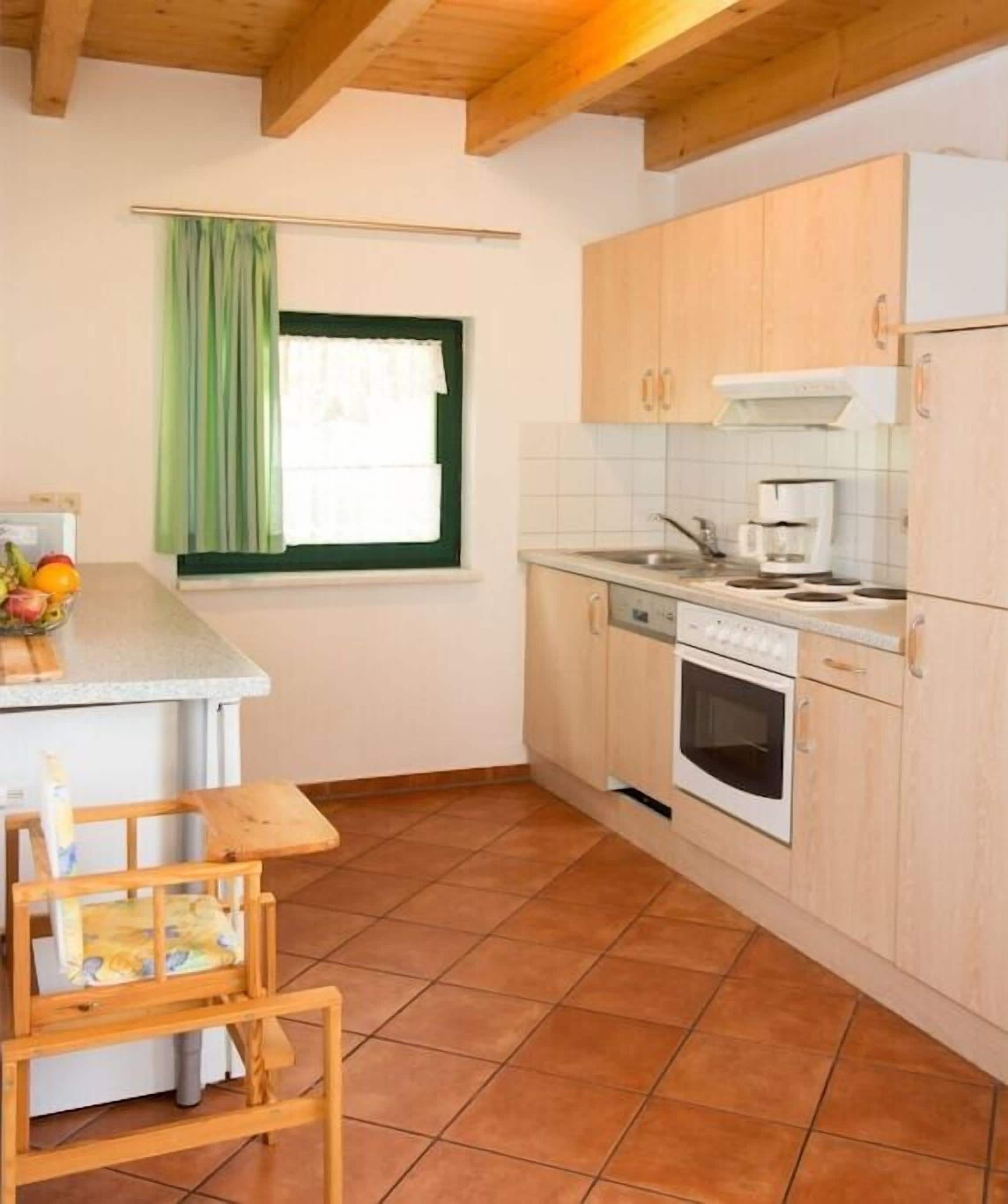 A kitchen with a stove, oven, and a window with a green curtain.