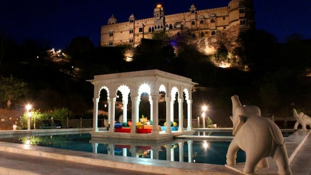 A night view of a historic building with a pool and a gazebo.