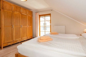 Ein Schlafzimmer mit zwei Betten, einem Holzschrank und einem Fenster.