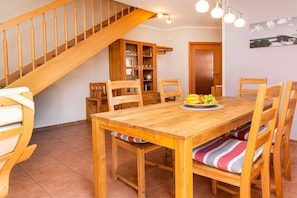Ein Holzespeisesaal mit Stühlen, einer Treppe und einem Bücherregal.