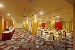 A conference room with rows of tables, chairs, and a carpeted floor. - Hotel Mumbai House (Udaipur)