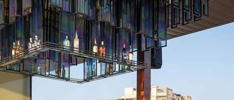 A rooftop bar with a glass ceiling, seating area, and bottles of liquor.