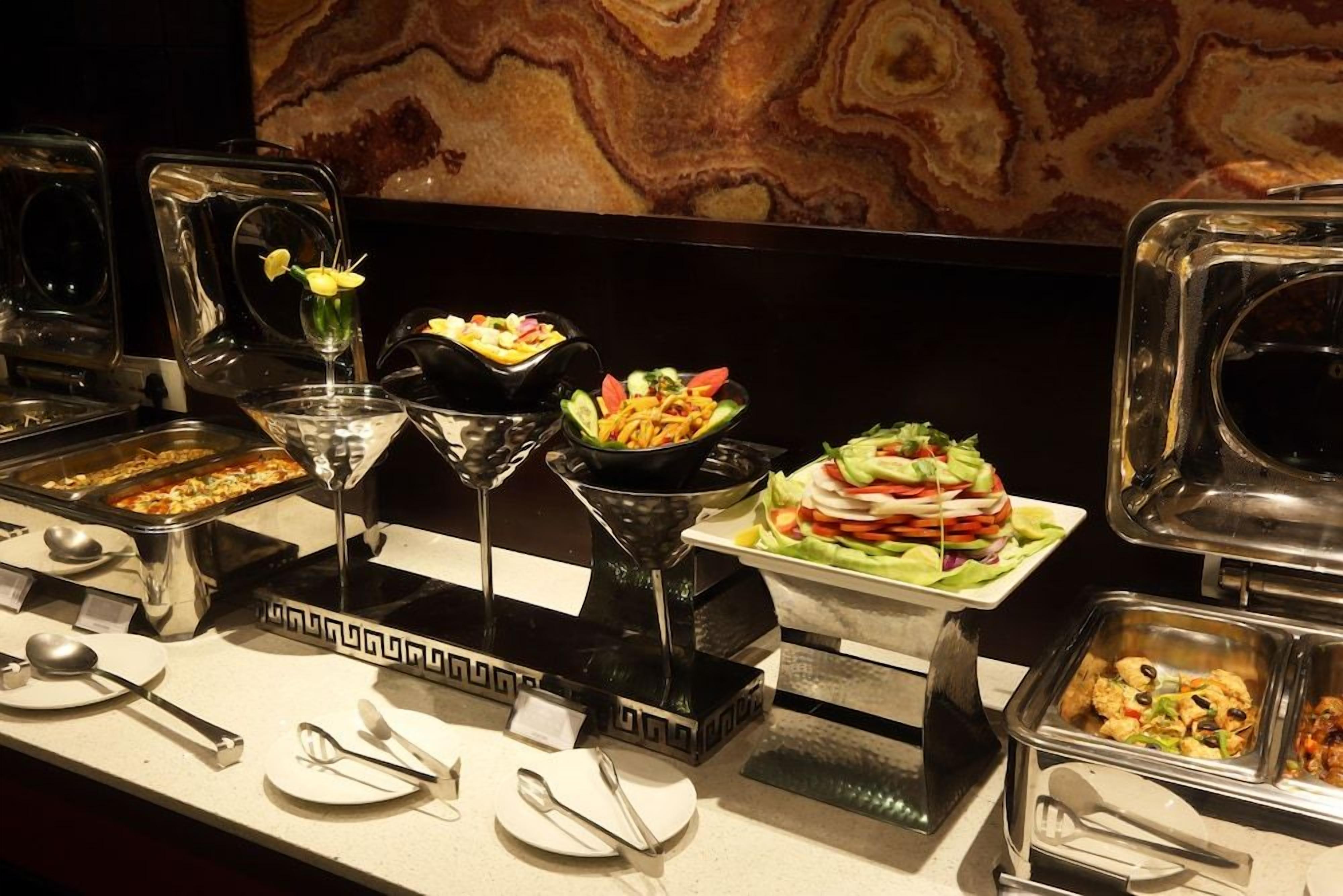 A buffet setup with various food items and serving utensils.