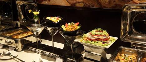 A buffet setup with various food items and serving utensils.