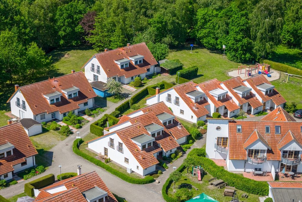 A residential area with multiple houses, each with a red-tiled roof and white walls.