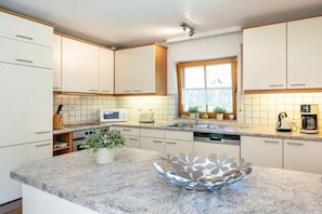 A modern kitchen with white cabinets, a granite countertop, and a window providing natural light. - 9/T6 holiday home park “Freesenbruch” (Zingst (Ostseeheilbad))