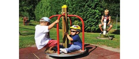 Two children playing on a playground equipment with a circular base and a central pole.