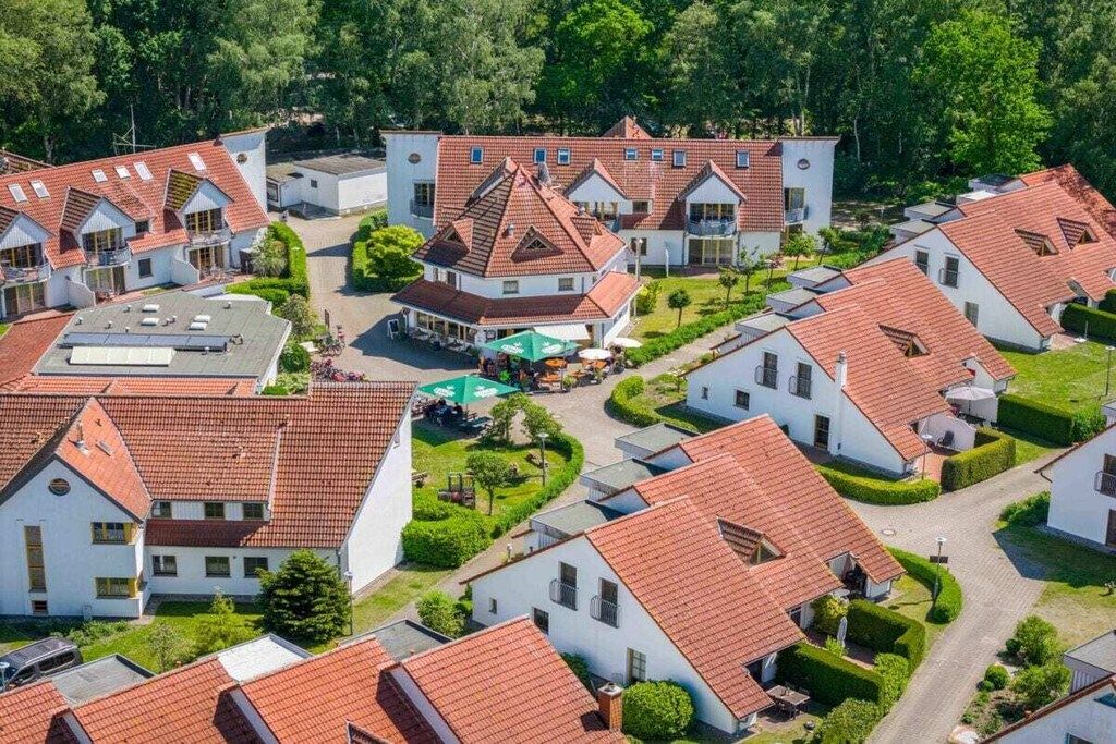 Un quartier résidentiel composé de plusieurs maisons aux toits recouverts de tuiles rouges et aux murs blancs, le tout entouré de verdure.