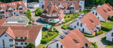 Un quartier résidentiel composé de plusieurs maisons aux toits recouverts de tuiles rouges et aux murs blancs, le tout entouré de verdure.