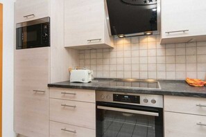 A kitchen with a microwave, toaster, stove, oven, and tiled backsplash. - 1.3/T2 holiday home park “Freesenbruch” (Zingst (Ostseeheilbad))