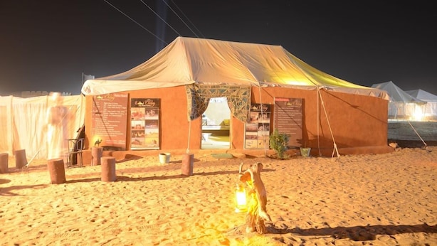 Una tienda de campaña en el desierto con un dosel, un cartel y un farol.
