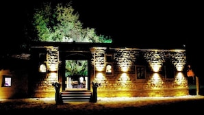 Un edificio de piedra con un arco central y escaleras que conducen a una puerta, iluminado por luces exteriores.