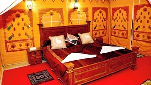 Una habitación con cama, almohadas, una mesita de noche y una lámpara.