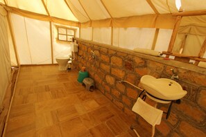 A tented bathroom with a toilet, sink, and stone wall. - The Chirag Desert Camp (Jaisalmer)