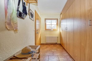A narrow hallway with a wooden wardrobe, a radiator, and a window with curtains. - 4.4/T3 holiday home park “Freesenbruch” (Zingst (Ostseeheilbad))
