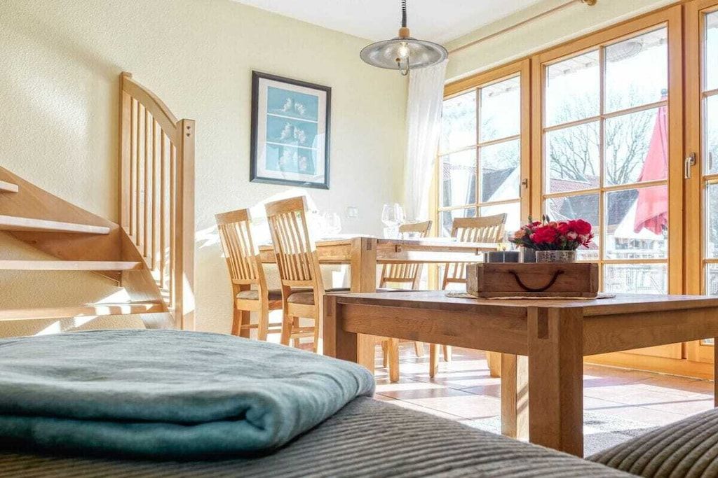 Une pièce comprenant une table à manger en bois, des chaises, un banc et une fenêtre avec des rideaux.