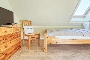 A bedroom with a wooden bed, a wooden dresser, a television, and a skylight. - 4.4/T3 holiday home park “Freesenbruch” (Zingst (Ostseeheilbad))
