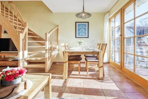 A dining area with a wooden table, chairs, and a staircase leading to a loft. - 4.4/T3 holiday home park “Freesenbruch” (Zingst (Ostseeheilbad))