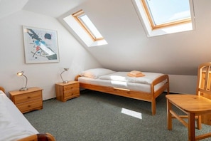 A bedroom with a sloped ceiling, a bed, two nightstands, a chair, and a skylight. - 2.5/T3 holiday home park “Freesenbruch” (Zingst (Ostseeheilbad))