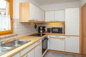 A compact kitchen with white cabinets, a stainless steel sink, a microwave, and a coffee maker. - 7/T5 holiday home park “Freesenbruch” (Zingst (Ostseeheilbad))