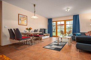 A modern living room with a dining area, a sofa, and a coffee table. - 1.2/T4 holiday home park “Freesenbruch” (Zingst (Ostseeheilbad))