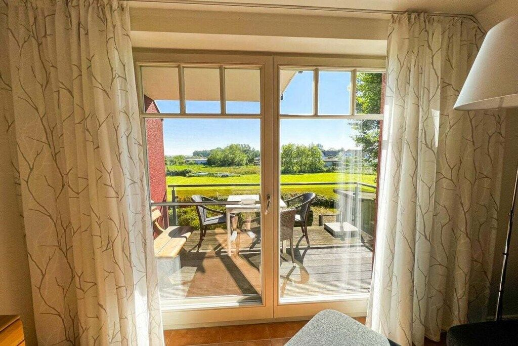 Una habitación con puerta corrediza de vidrio que da a una terraza exterior con mesa y sillas.