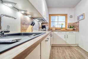 A modern kitchen with a wooden countertop, stainless steel sink, and white cabinets. - 6a/T5 in the "Freesenbruch" holiday park (Zingst (Ostseeheilbad))