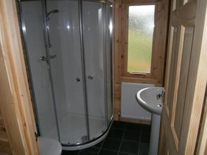 A bathroom with a glass shower enclosure, a toilet, a sink, and a window. - Long Mountain Centre (Shrewsbury)
