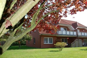 A two-story brick house with a red roof, a covered porch, and a small front yard. - Holiday apartment with 2 bedrooms (Zingst (Ostseeheilbad))