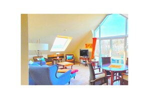 A spacious living area with a large window, a television, and a dining table. - Residence on the Beach 2-39 (Zingst (Ostseeheilbad))