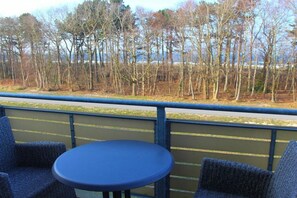 A balcony with a table and chairs, overlooking a forested area. - Residence on the Beach 2-39 (Zingst (Ostseeheilbad))
