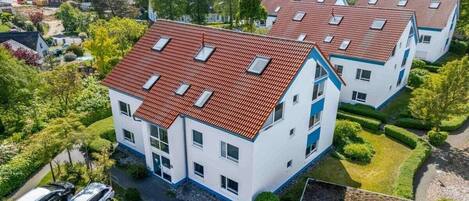 A residential building with multiple units, each featuring a red-tiled roof and white walls.