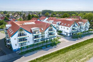 A modern multi-story residential building with balconies, a flat roof, and a paved driveway. - Residence on the Beach 2-39 (Zingst (Ostseeheilbad))