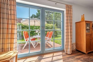 Ein Zimmer mit einer großen Schiebeglastür, die auf eine Terrasse mit Tisch und Stühlen führt.