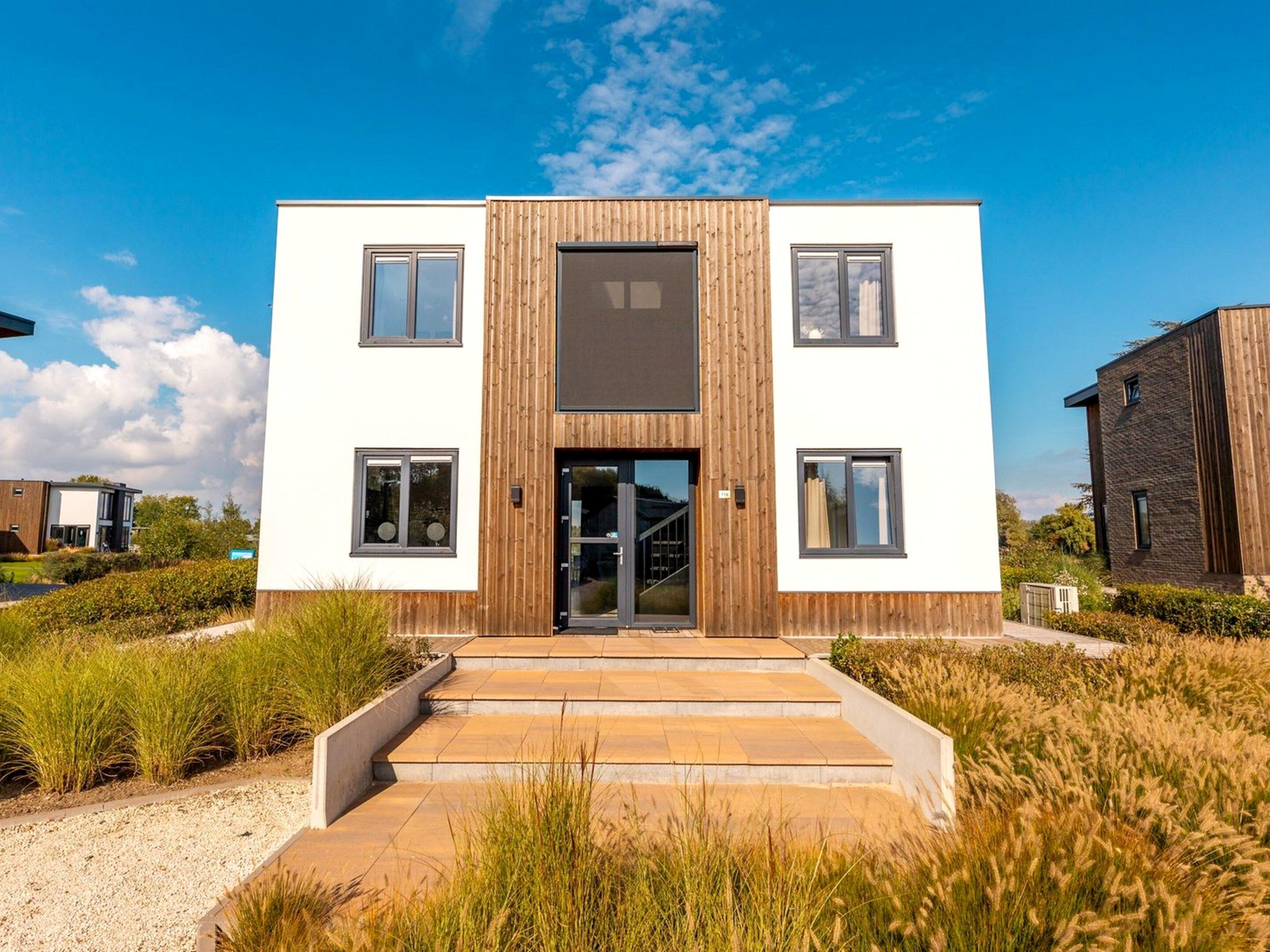 A modern two-story building with a central entrance, surrounded by a well-maintained garden.