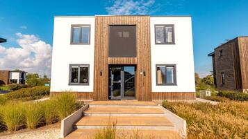 A modern two-story building with a central entrance, surrounded by a well-maintained garden.