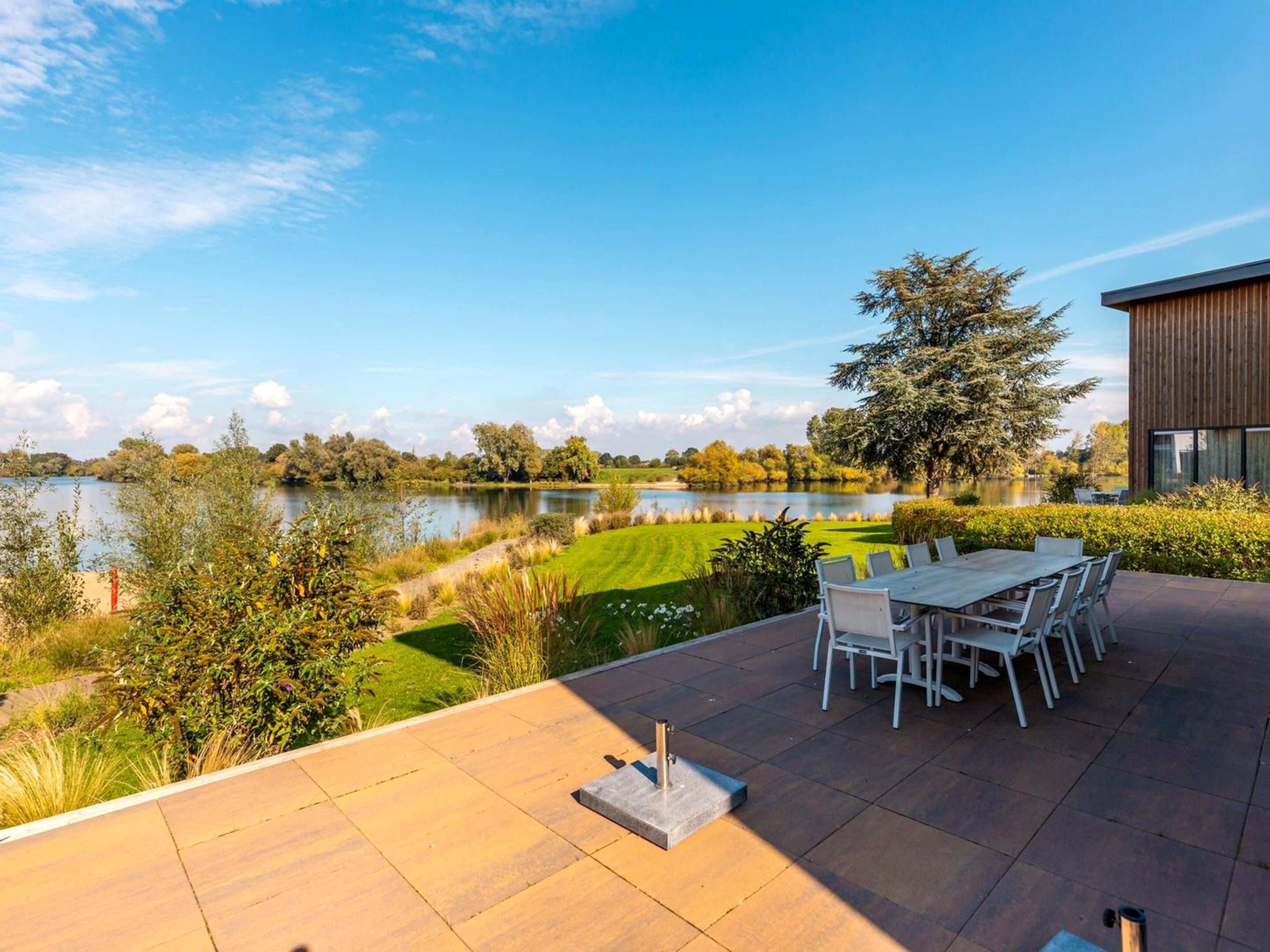 A patio with a table and chairs overlooking a lake.