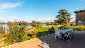 A patio with a table and chairs overlooking a lake.