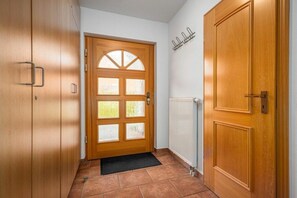 A hallway with a wooden door, a radiator, and a black mat. - 10a/T6 Holiday Park "Freesenbruch" (Zingst (Ostseeheilbad))