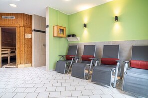 A sauna room with wooden walls, a bench, and four reclining chairs with red cushions. - 10a/T6 Holiday Park "Freesenbruch" (Zingst (Ostseeheilbad))