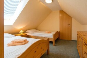Ein kleiner, gemütlicher Raum mit zwei Holzbett, einem Holzschrank und einem Oberlicht.